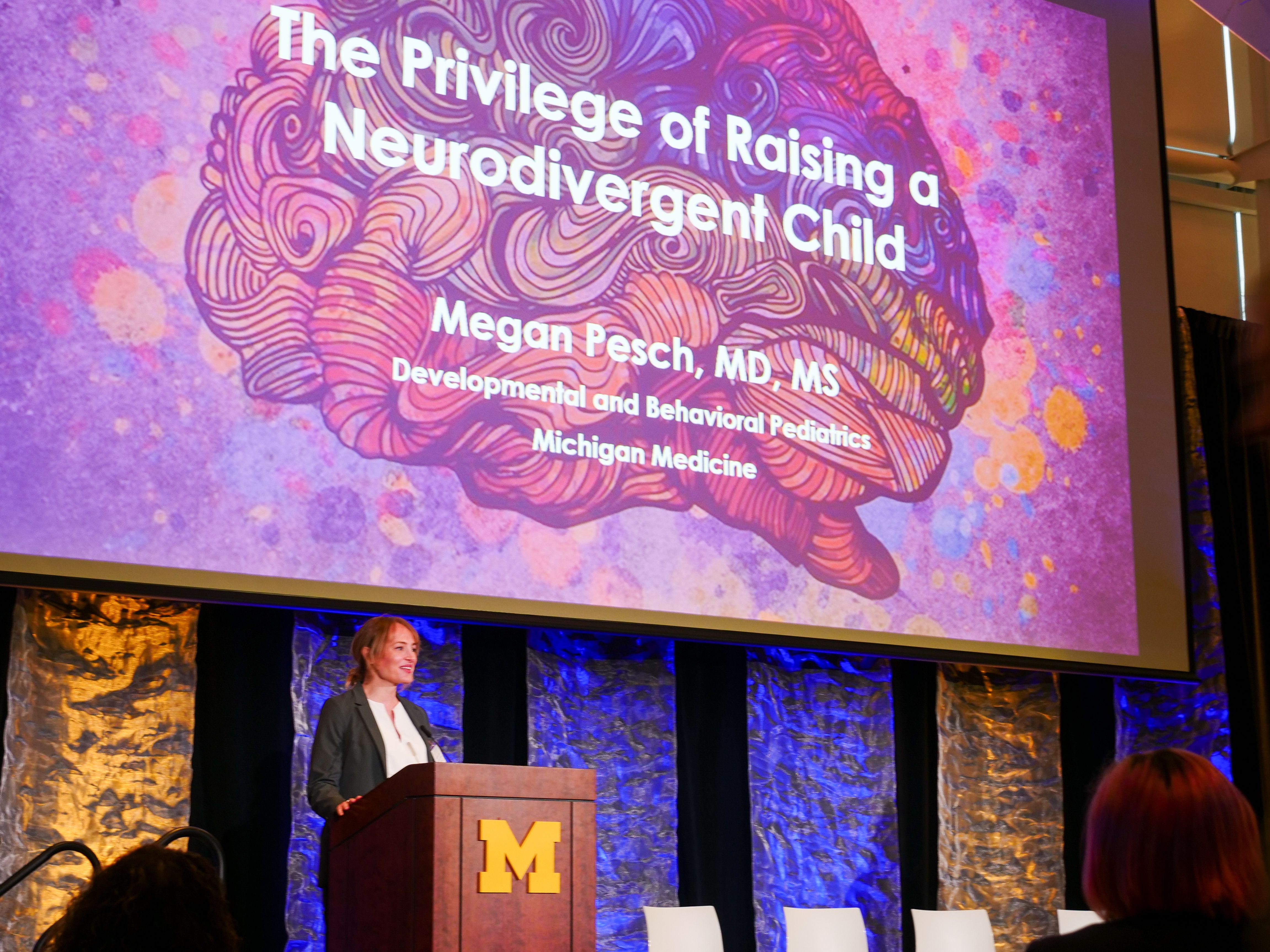 A person at a lectern in front of a screen that says The Privilege of Raising a Neurodivergent Child