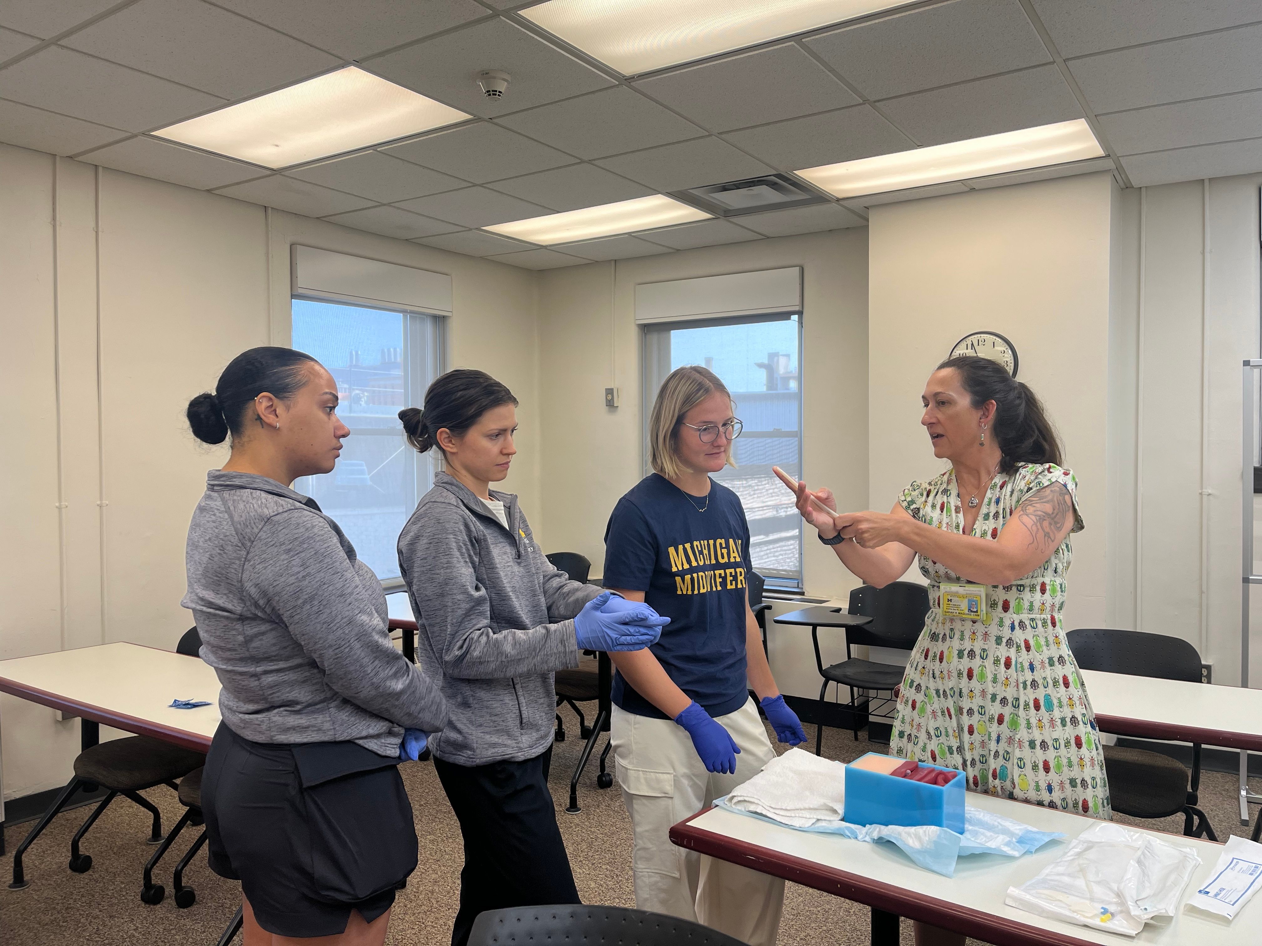 An instructor demonstrating a procedure in front of students wearing gloves