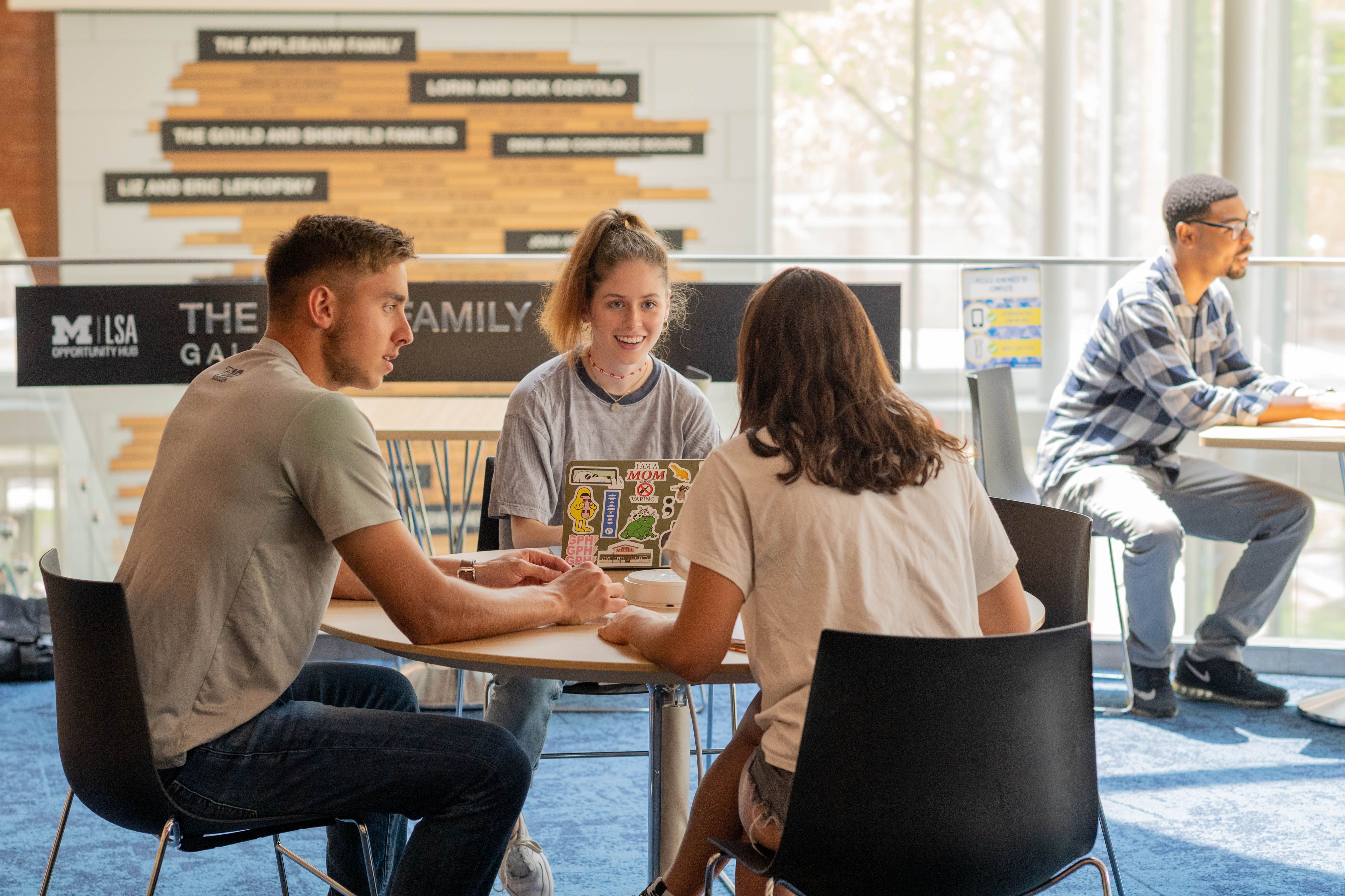 Students having a conversation at a table in the LSA Opportunity Hub