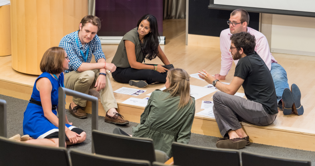 People sitting on the floor while working on an exercise with papers in front of them