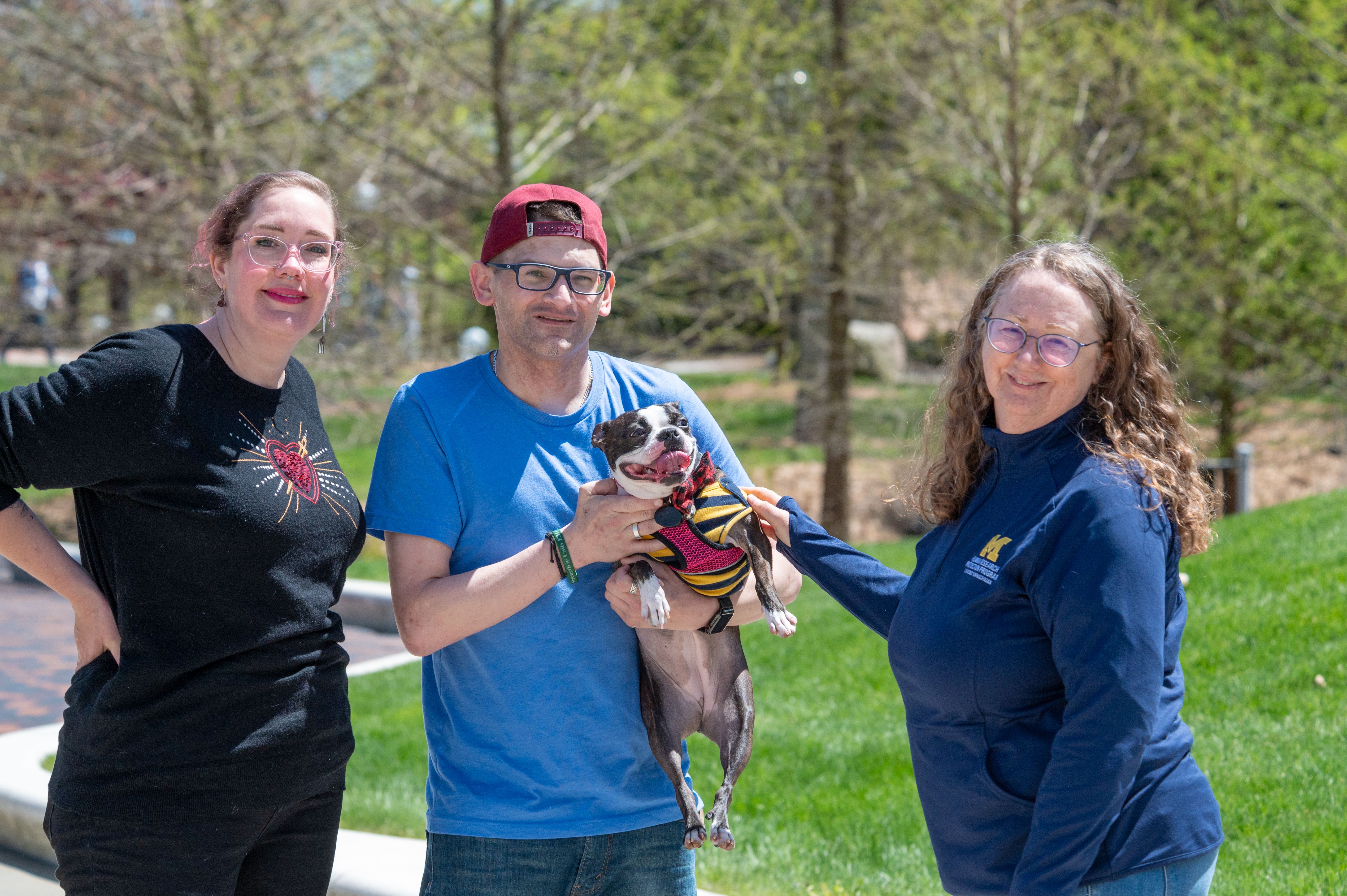 People standing together and one is holding a dog