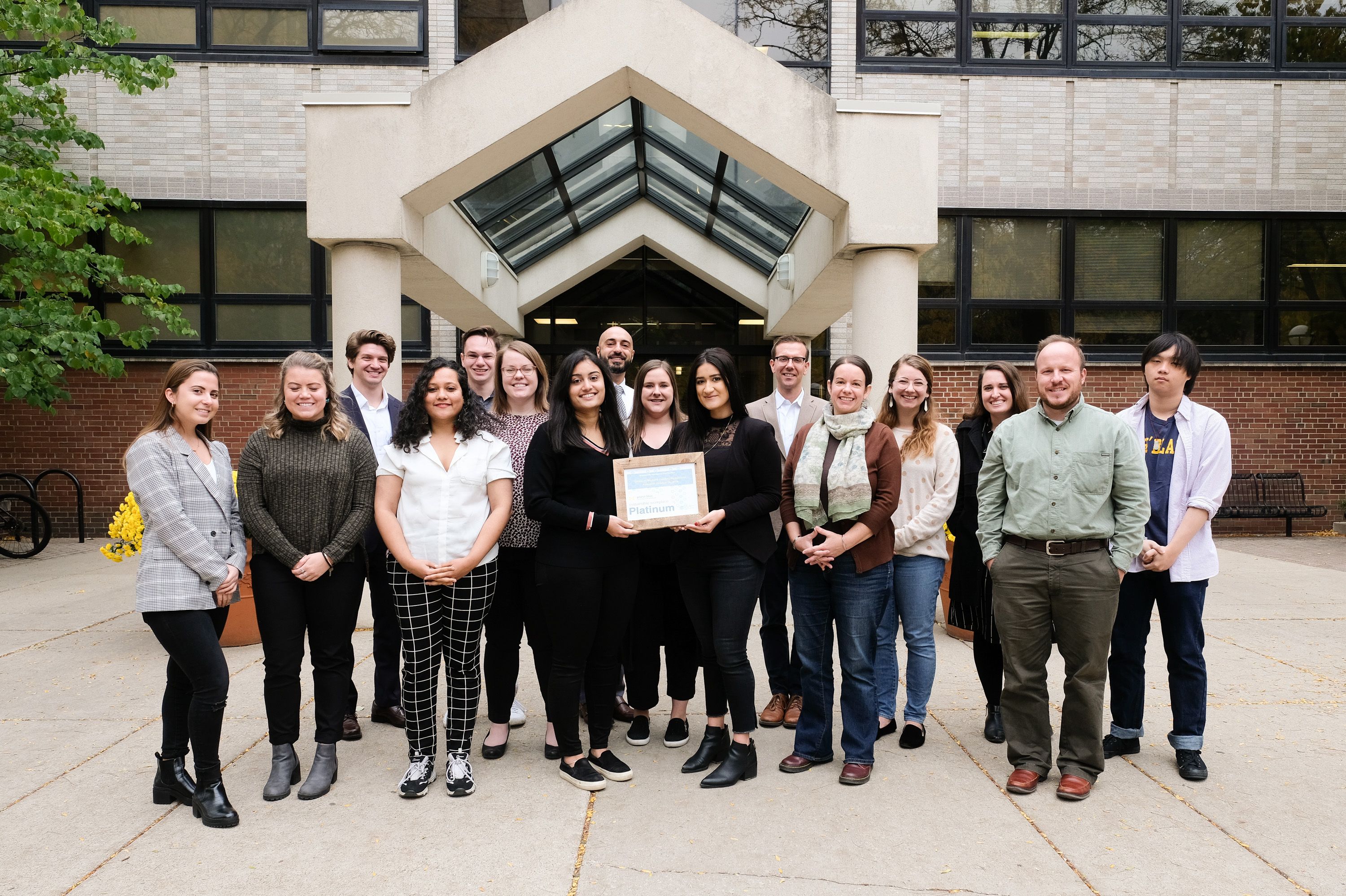 A group of people standing in front of the ISR building and holding a certificate