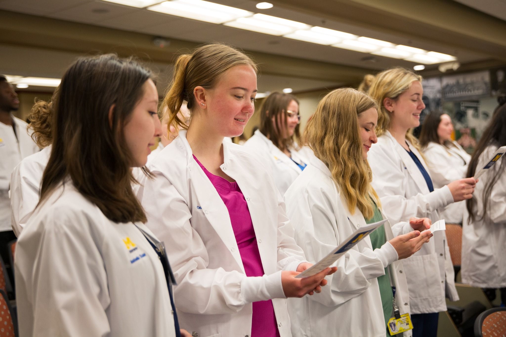 Dentistry students wearing white coats and reading handouts