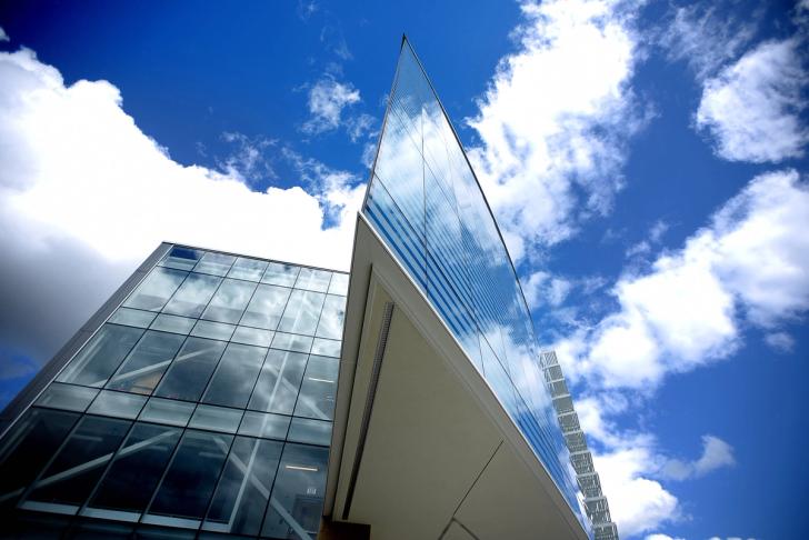 Looking up at the glass exterior of the Ford Robotics against a blue sky with clouds